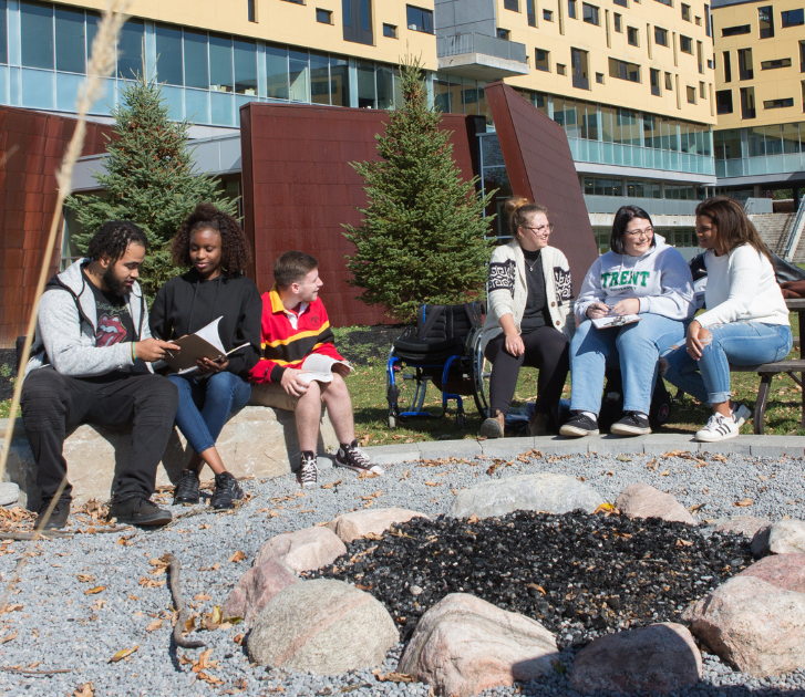 Trent students sitting outside Peter Gzowski College on Campus